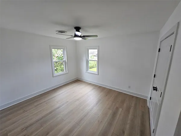 a view of an empty room with a window and wooden floor
