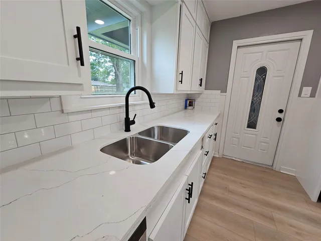 a kitchen with white cabinets and sink