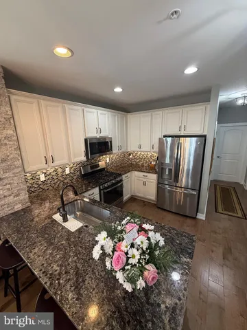 a kitchen with granite countertop a refrigerator sink stove microwave and cabinets