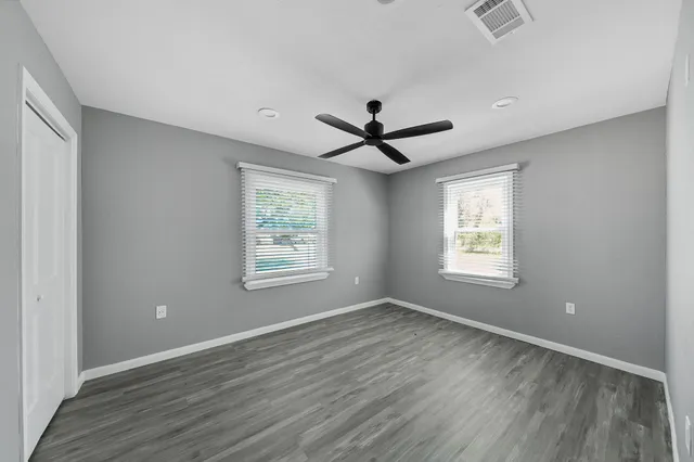 a view of a big room with wooden floor and windows