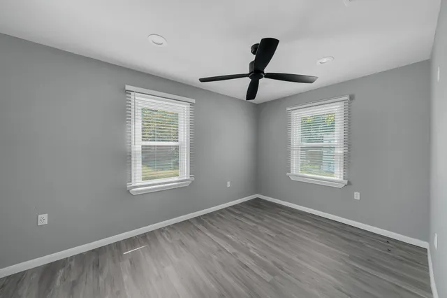 a view of an empty room with window and wooden floor