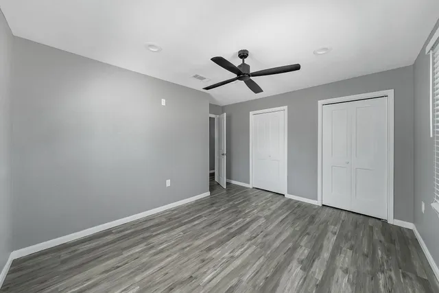 a view of a big room with wooden floor and a ceiling fan