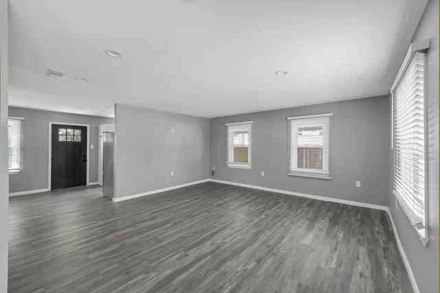 an empty room with wooden floor and windows