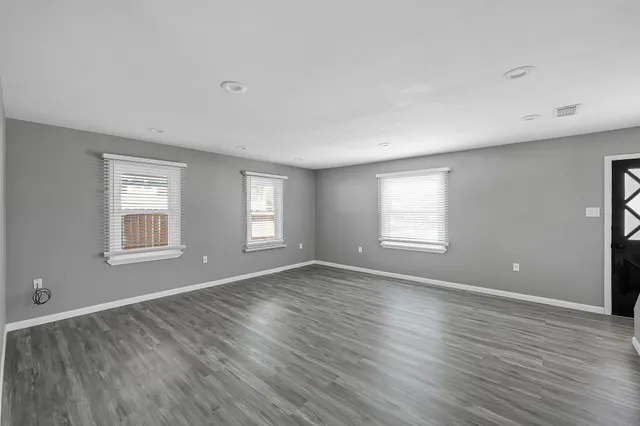 an empty room with wooden floor and windows