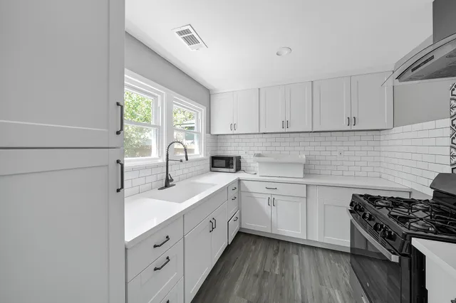 a kitchen with cabinets appliances a sink and a window
