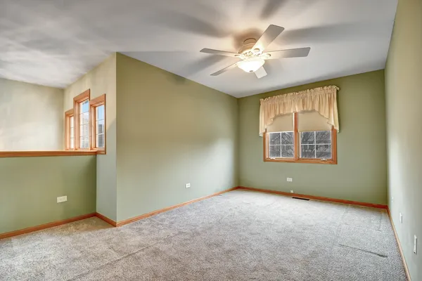 an empty room with windows and fan