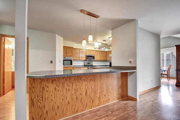 a view of a kitchen with kitchen island a sink wooden floor and a window