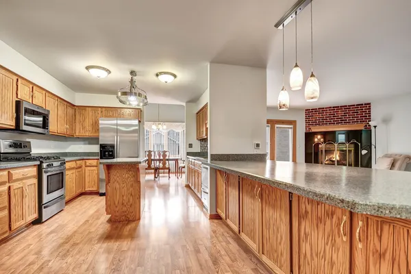 a large kitchen with a center island wooden floor stainless steel appliances and living room view