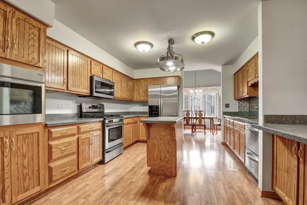 a large kitchen with stainless steel appliances granite countertop a large center island attached withe living room
