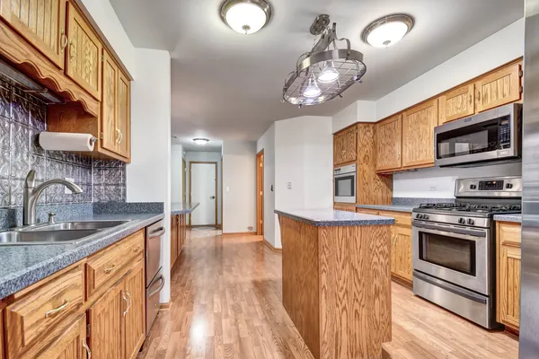 a kitchen with stainless steel appliances granite countertop a stove top oven a sink dishwasher a dining table and chairs with wooden floor