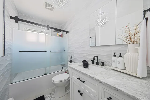 a bathroom with a granite countertop sink toilet a mirror and shower