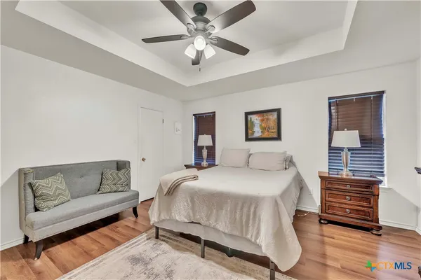 a bedroom with a bed couches and a ceiling fan