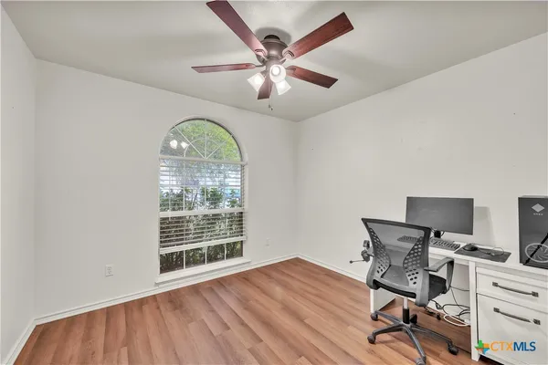 a workspace with wooden floor a chandelier fan and windows