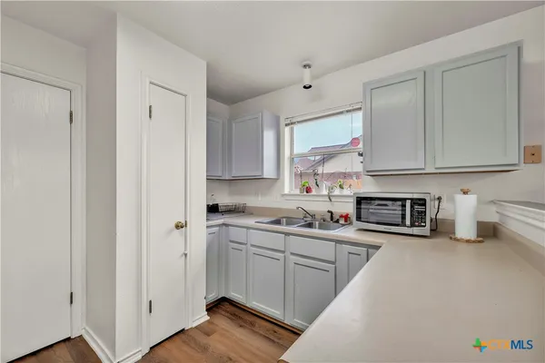 a kitchen with stainless steel appliances granite countertop a stove a sink and a refrigerator with white cabinets