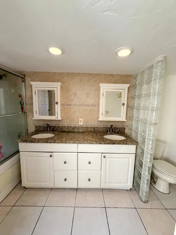 a bathroom with a granite countertop sink a toilet and mirror