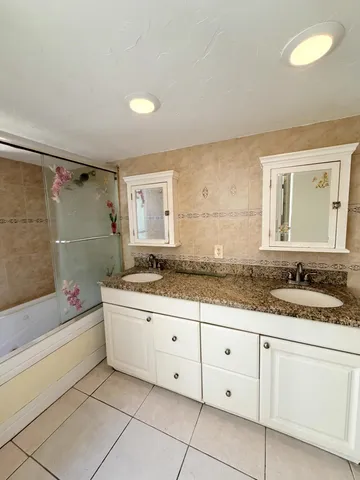 a bathroom with a granite countertop sink a mirror and a bathtub