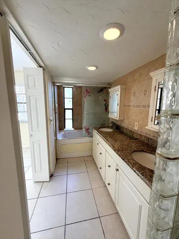 a spacious bathroom with a granite countertop sink a mirror and a bathtub