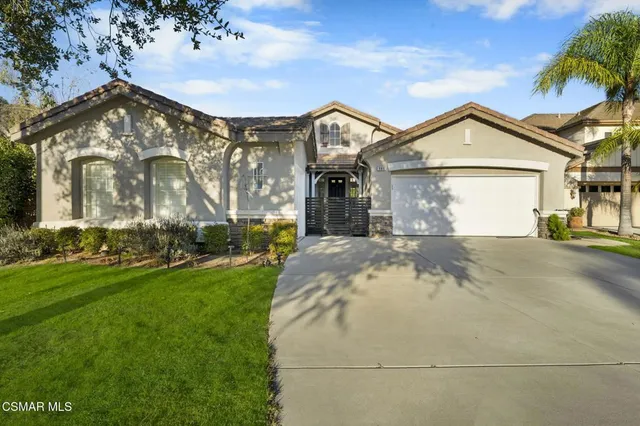 a view of a white house with a small yard and large tree