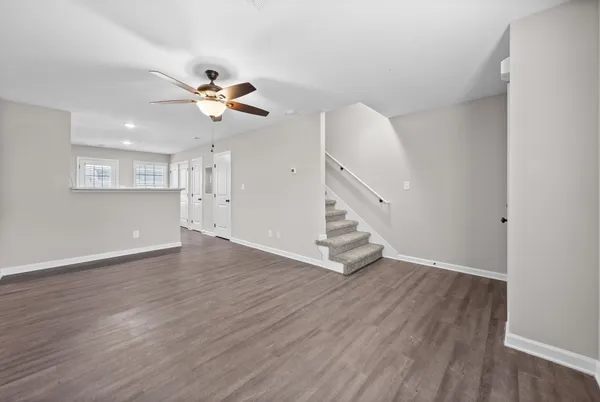 a view of an empty room with wooden floor and a ceiling fan