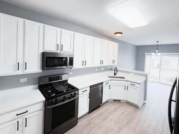 a kitchen with stainless steel appliances a sink dishwasher stove and white cabinets