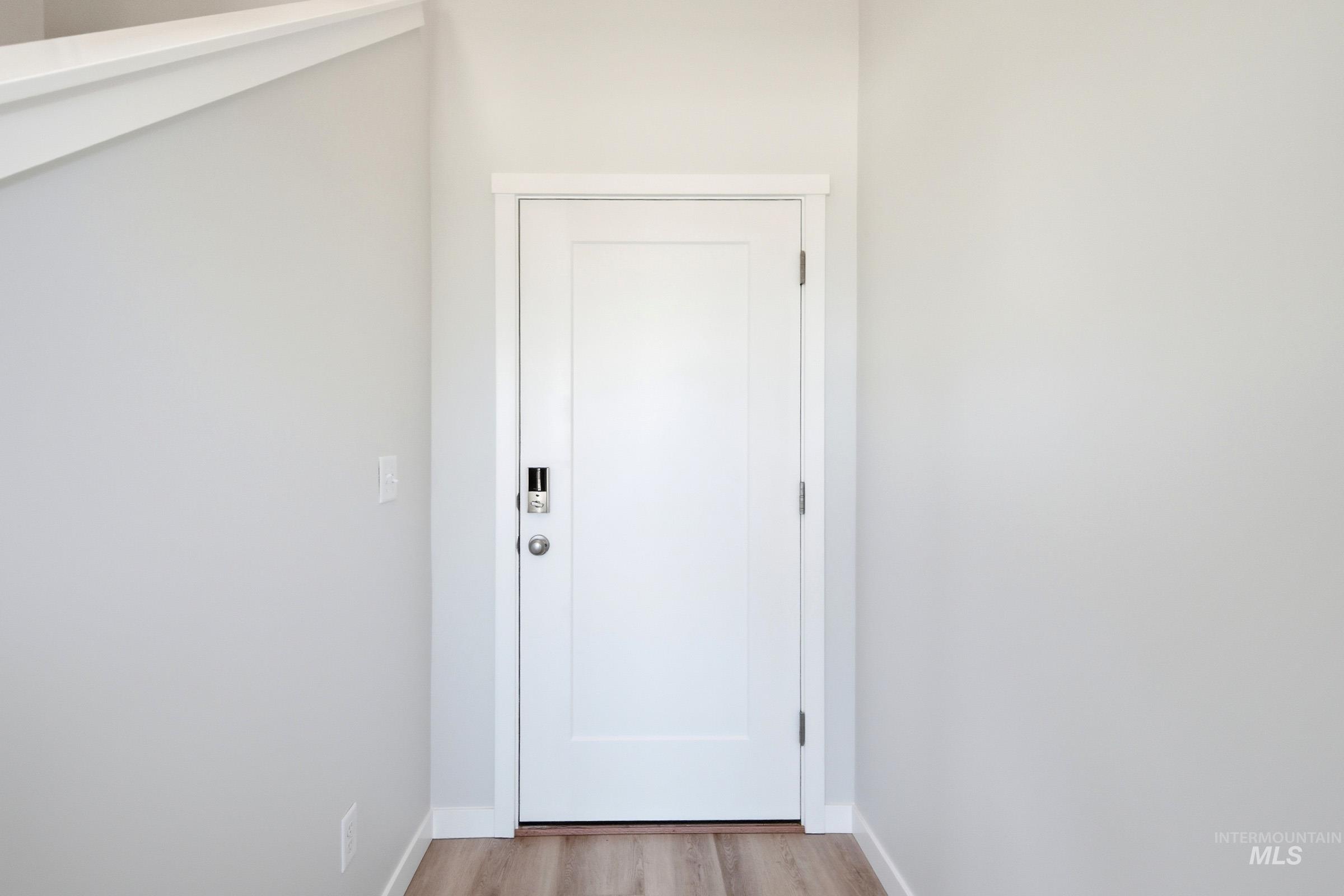 10812 Rutland Street Caldwell, ID 83605 - Photo 2 of 21 Interior entry door with clean white trim, a modern smart lock, and wood-finish flooring