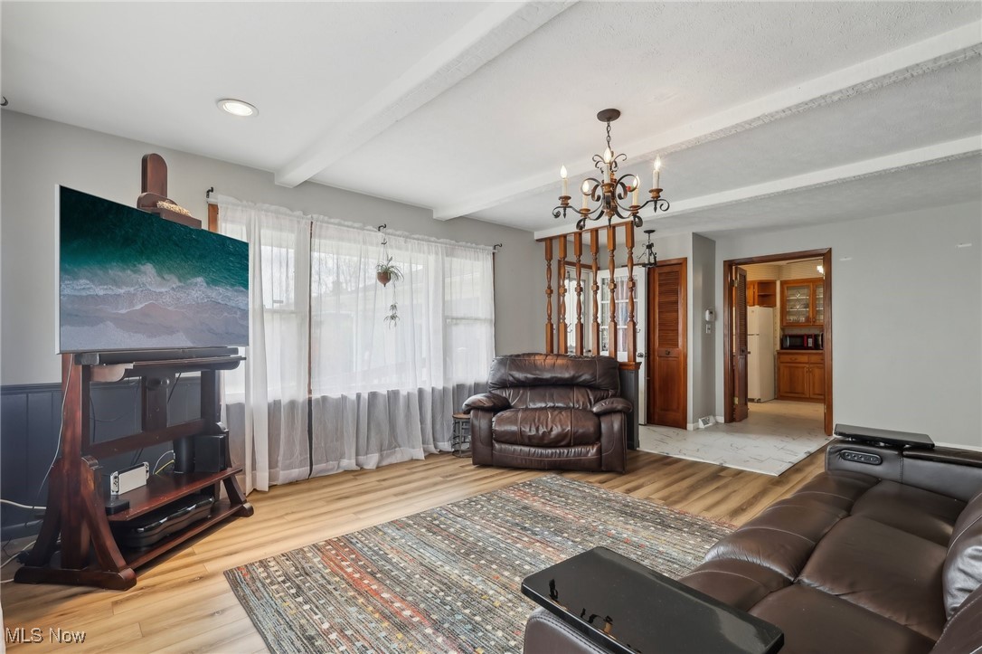 13676 Whitney Road Strongsville, OH 44136 - Photo 15 of 46 Living room featuring beam ceiling, wood finished floors, and an inviting chandelier