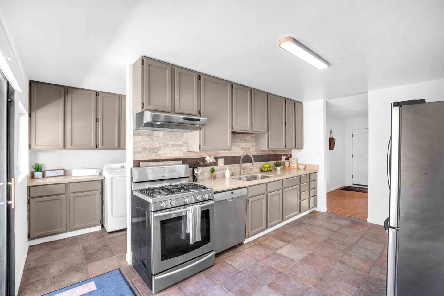 5519 Amend Road El Sobrante, CA 94803 - Photo 14 of 38 a kitchen with stainless steel appliances granite countertop a stove top oven a refrigerator and a sink with wooden cabinets