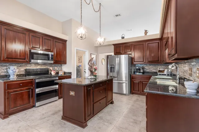 a kitchen with stainless steel appliances granite countertop a stove top oven a refrigerator a sink and dishwasher