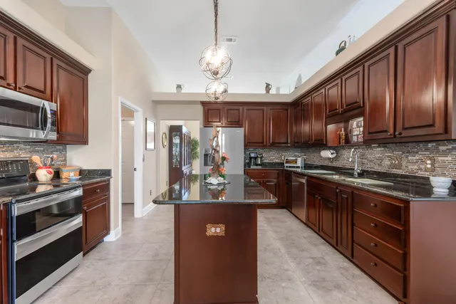 a kitchen with stainless steel appliances granite countertop wooden cabinets a stove a sink and a refrigerator