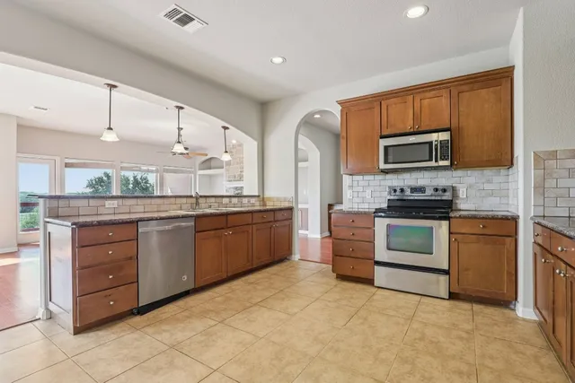 a kitchen with stainless steel appliances granite countertop a stove top oven a sink dishwasher a refrigerator and a oven