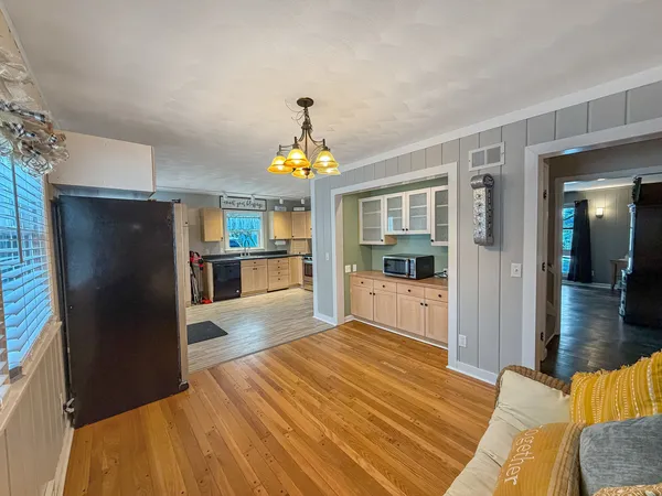 a dining room with wooden floor furniture and a chandelier