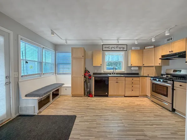 a kitchen with stainless steel appliances granite countertop a refrigerator a sink dishwasher a stove and white countertops with wooden floor