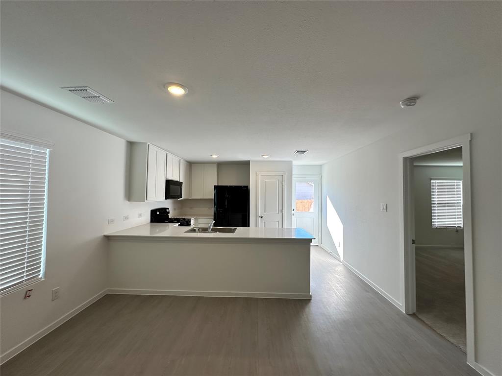 1034 Raintree Road Princeton, TX 75407 - Photo 3 of 17 a living room with stainless steel appliances a kitchen island hardwood floor and a sink