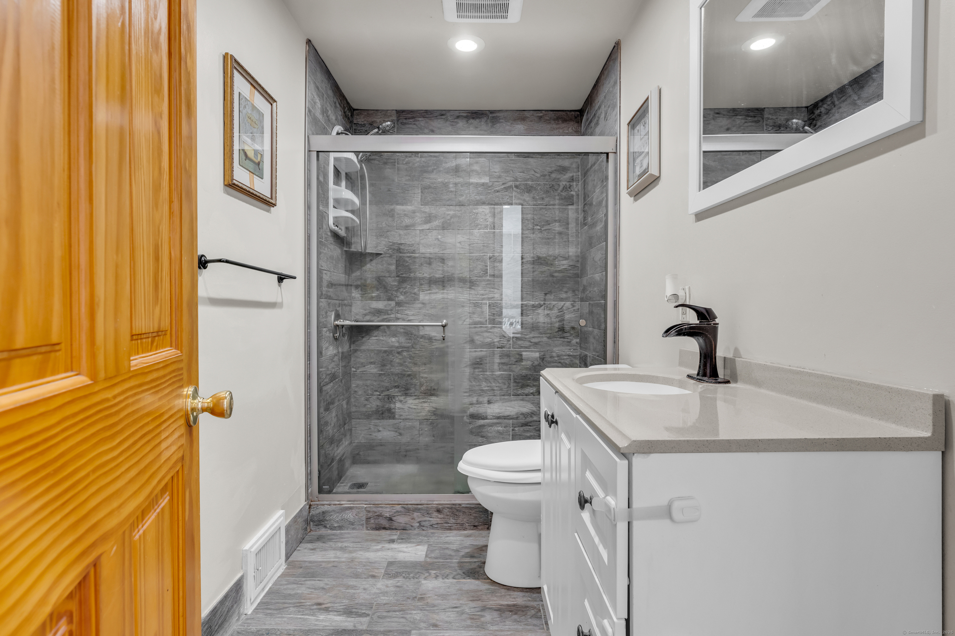 64 Dohm Avenue Guilford, CT 06437 - Photo 24 of 38 a bathroom with a granite countertop sink a toilet a mirror and shower