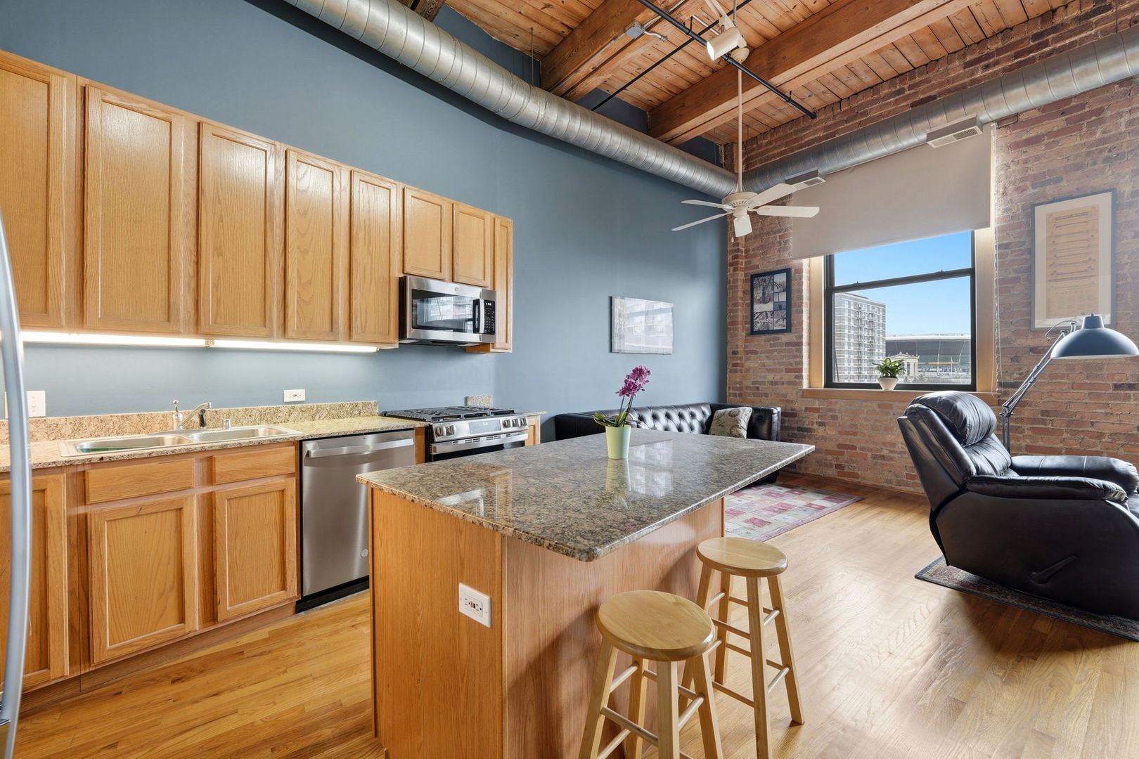 1550 South Indiana Avenue, Unit 401 Chicago, IL 60605 - Photo 4 of 20 a kitchen with stainless steel appliances granite countertop a stove a sink dishwasher and white cabinets with wooden floor