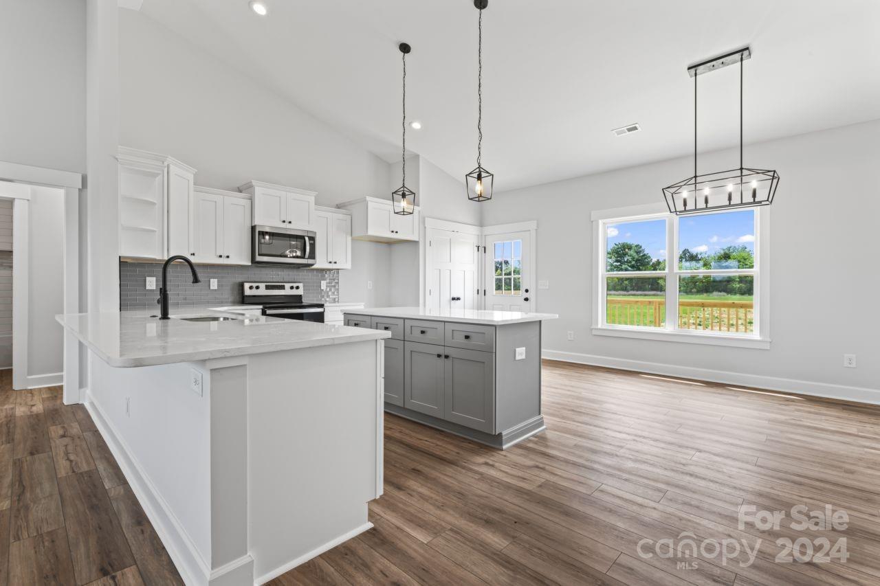 234 Briggs Road Salisbury, NC 28147 - Photo 7 of 35 a kitchen with kitchen island white cabinets stainless steel appliances a sink a window and wooden floor