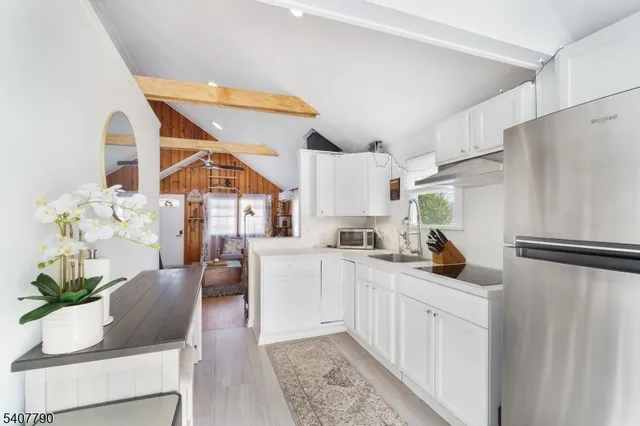 a kitchen with stainless steel appliances granite countertop a refrigerator a sink dishwasher and white cabinets with wooden floor