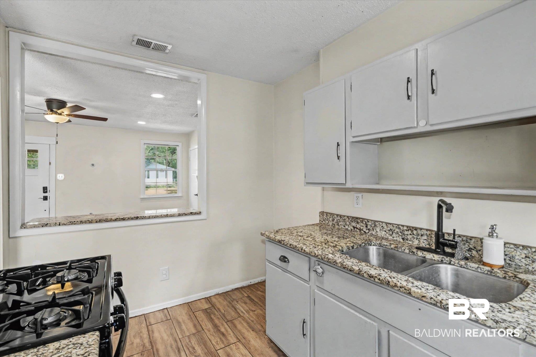 5117 Norton Lane Mobile, AL 36608 - Photo 12 of 35 Kitchen with black gas stove, light stone counters, wood tiled floors, a ceiling fan, and a textured ceiling
