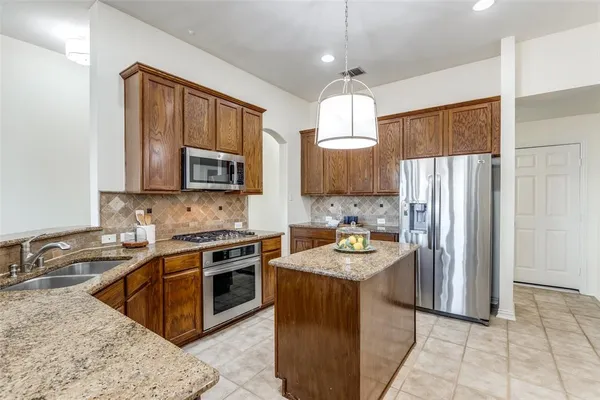a kitchen with stainless steel appliances granite countertop a sink stove microwave and refrigerator