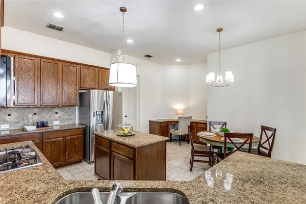 a kitchen with sink refrigerator dining table and chairs