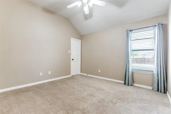 an empty room with a chandelier fan and windows