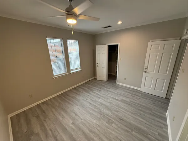 an empty room with wooden floor and windows