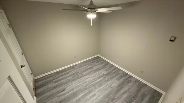 en empty room with wooden floor and fan