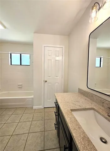 a bathroom with a granite countertop sink a mirror and a bathtub