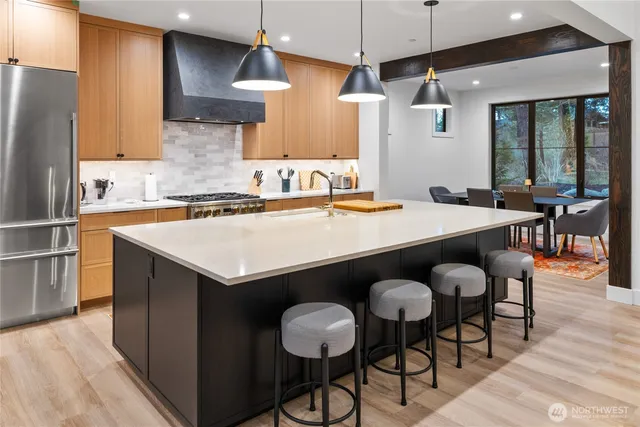 a kitchen with stainless steel appliances a table chairs sink and wooden floor