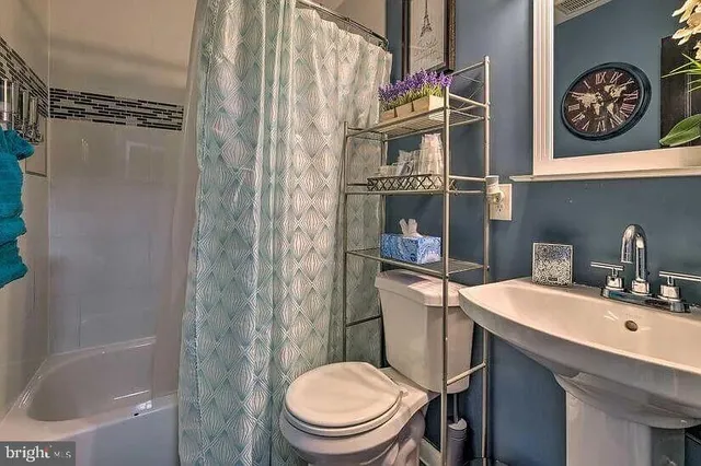 a bathroom with a sink a toilet and a shower curtain