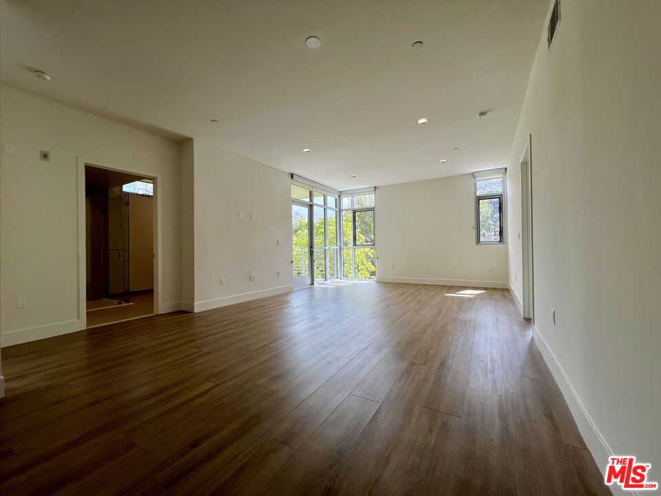 11715 Bellagio Road, Unit 204 Los Angeles, CA 90049 - Photo 6 of 27 a view of an empty room with wooden floor and windows