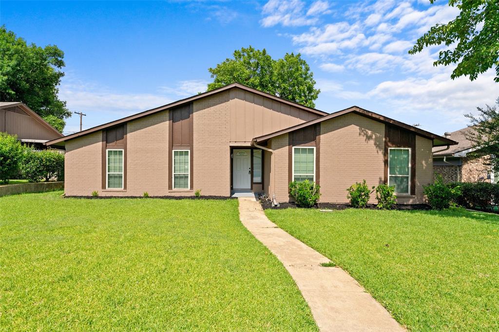 Mid-century inspired home with a front yard, board and batten siding, and brick siding