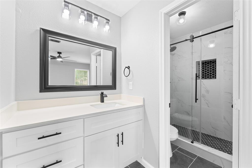 1137 Via Balboa Mesquite, TX 75150 - Photo 12 of 15 Bathroom featuring vanity, a marble finish shower, ceiling fan, dark tile patterned flooring, and a textured wall