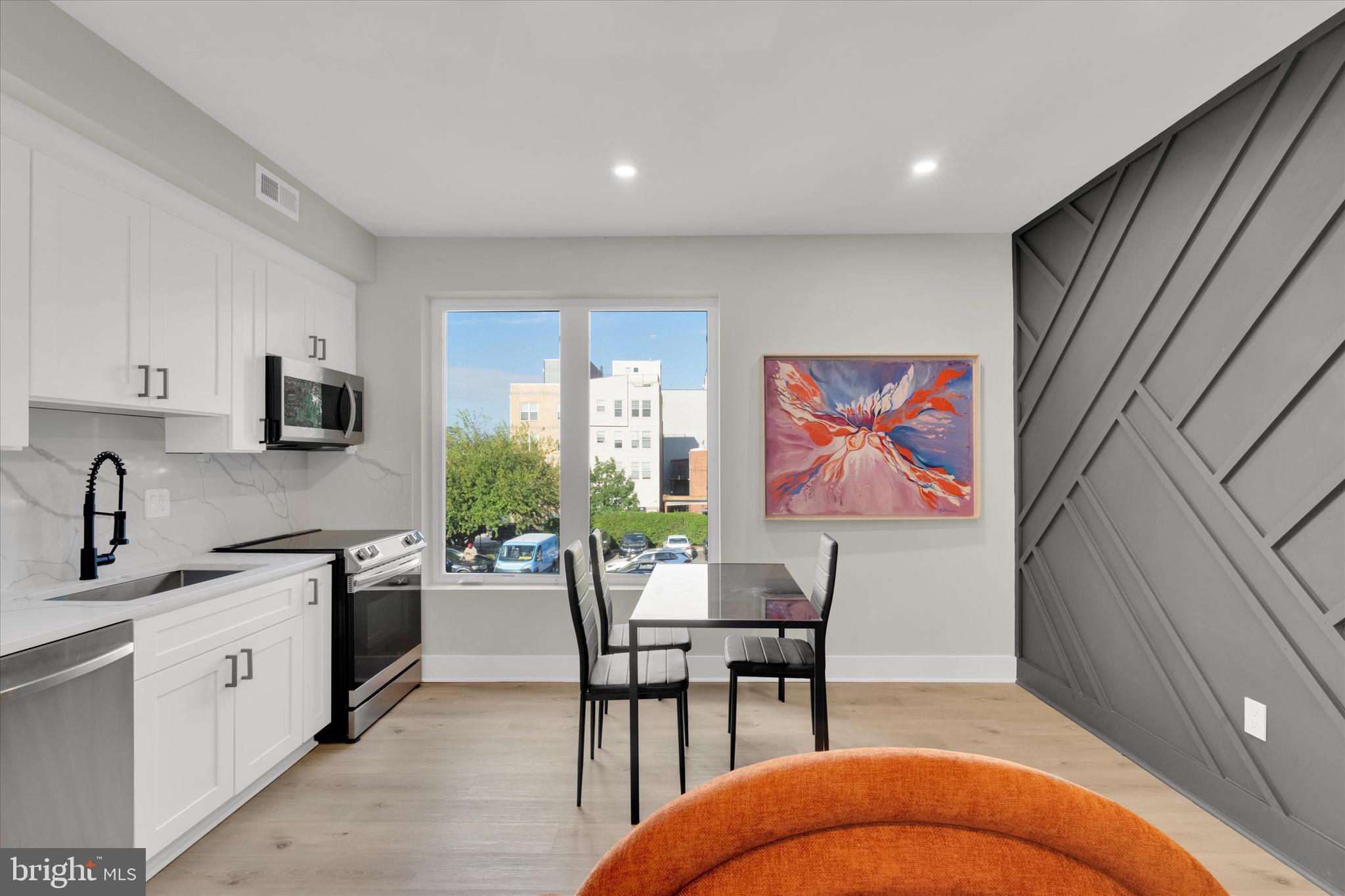 1915 Benning Road Northeast, Unit 9 401 Washington, DC 20002 - Photo 4 of 19 a open kitchen with stainless steel appliances granite countertop a stove top oven a sink dishwasher and white cabinets with wooden floor